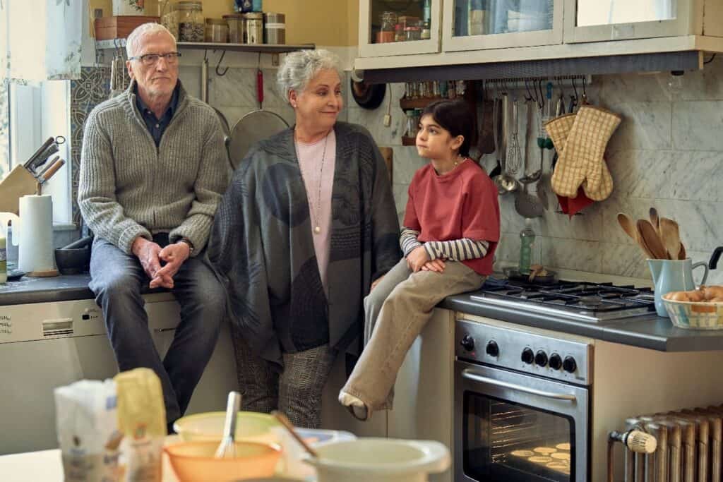 Drei Personen in einer gemütlichen Küche, Gespräch im Mittelpunkt.