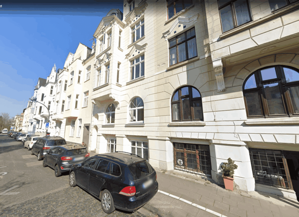 Moderne Gebäudefassade in Berlin mit Parkplätzen vor der Tür.