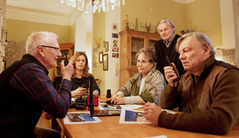 Altes Team bei einer strategischen Besprechung mit Kamera und Notizen.